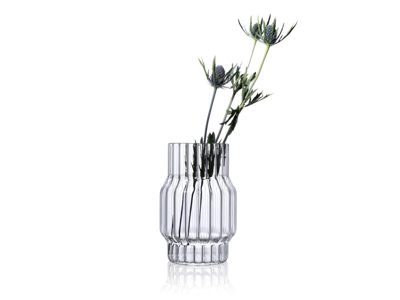 Small designer vase in fluted glass with flowers for home decor. 