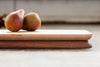 Maple side up on a rectangular cutting board composed of walnut and maple, styled with two pears. 